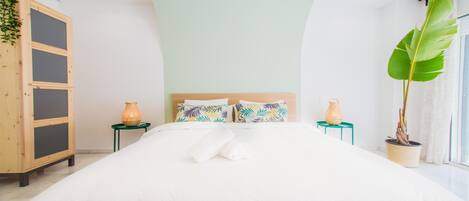 Un dormitorio moderno con una cama grande, dos mesitas de noche, un armario de madera y un amplio ventanal con vistas.