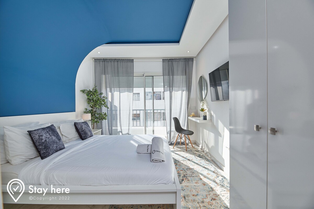 Una habitación de hotel moderna con una cama grande, un escritorio y vistas a la ciudad.