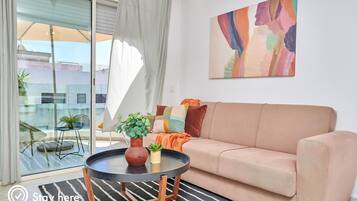 A living room with a beige sofa, a round black coffee table, and a painting on the wall.