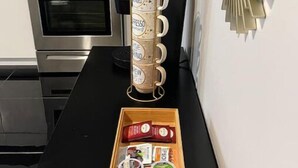 Uma cozinha com eletrodomésticos de aço inoxidável, uma cafeteira e uma bandeja com cápsulas de café.