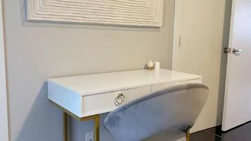 Een kamer met een wit bureau, een grijze stoel en een decoratief wandobject.