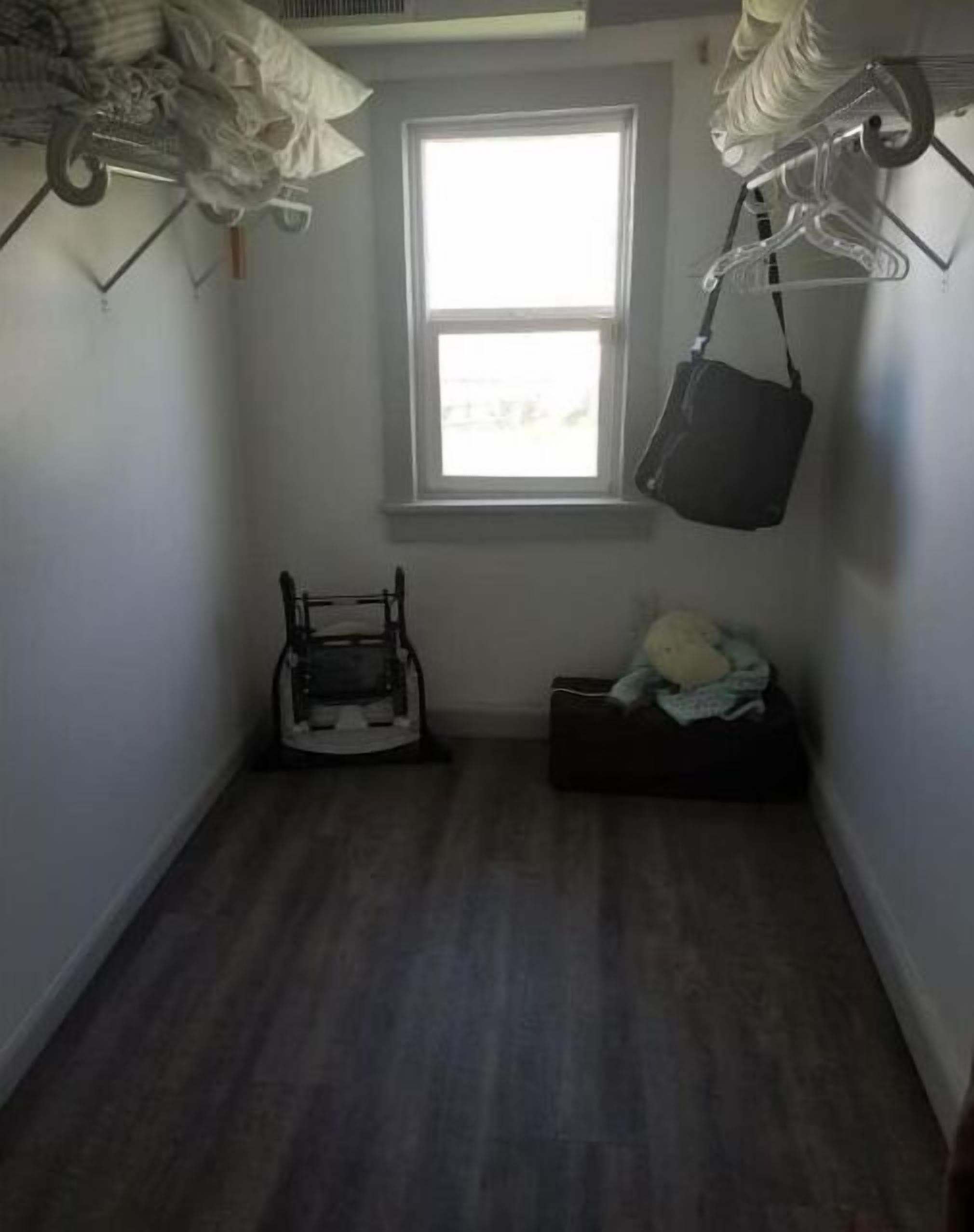A small, dimly lit room with a window, a chair, and a small table.