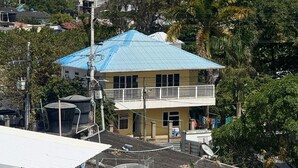 A coastal building with a blue roof, surrounded by lush greenery and a view of the ocean. - Aloha Beach Sai (San Andrés)