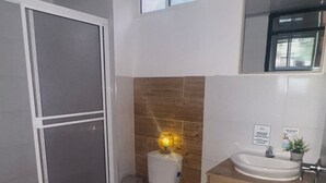 A bathroom with a toilet, sink, and shower area. - Aloha Beach Sai (San Andrés)