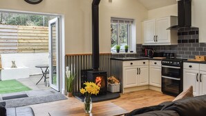 Une cuisine moderne avec des meubles blancs, une cuisinière noire et un coin repas comprenant une table et des chaises.