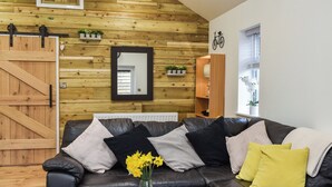 Un salon avec un canapé en cuir noir, une table basse en bois et un miroir au mur.