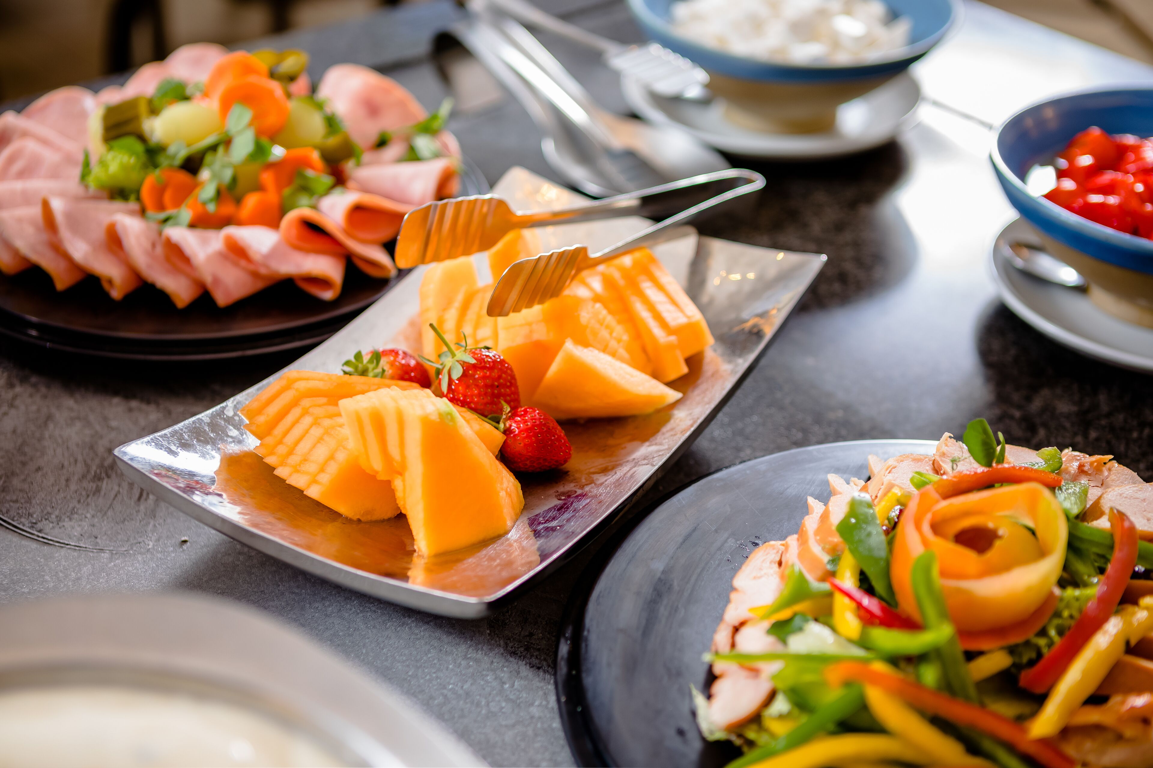 A variety of food items on a table, including sliced meats, cheese, and vegetables.