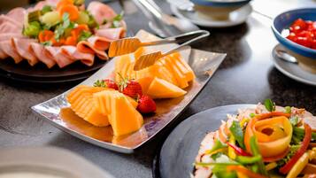 A variety of food items on a table, including sliced meats, cheese, and vegetables.
