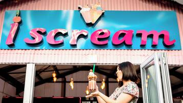 A storefront with a sign reading "I scream" and a person holding a drink.