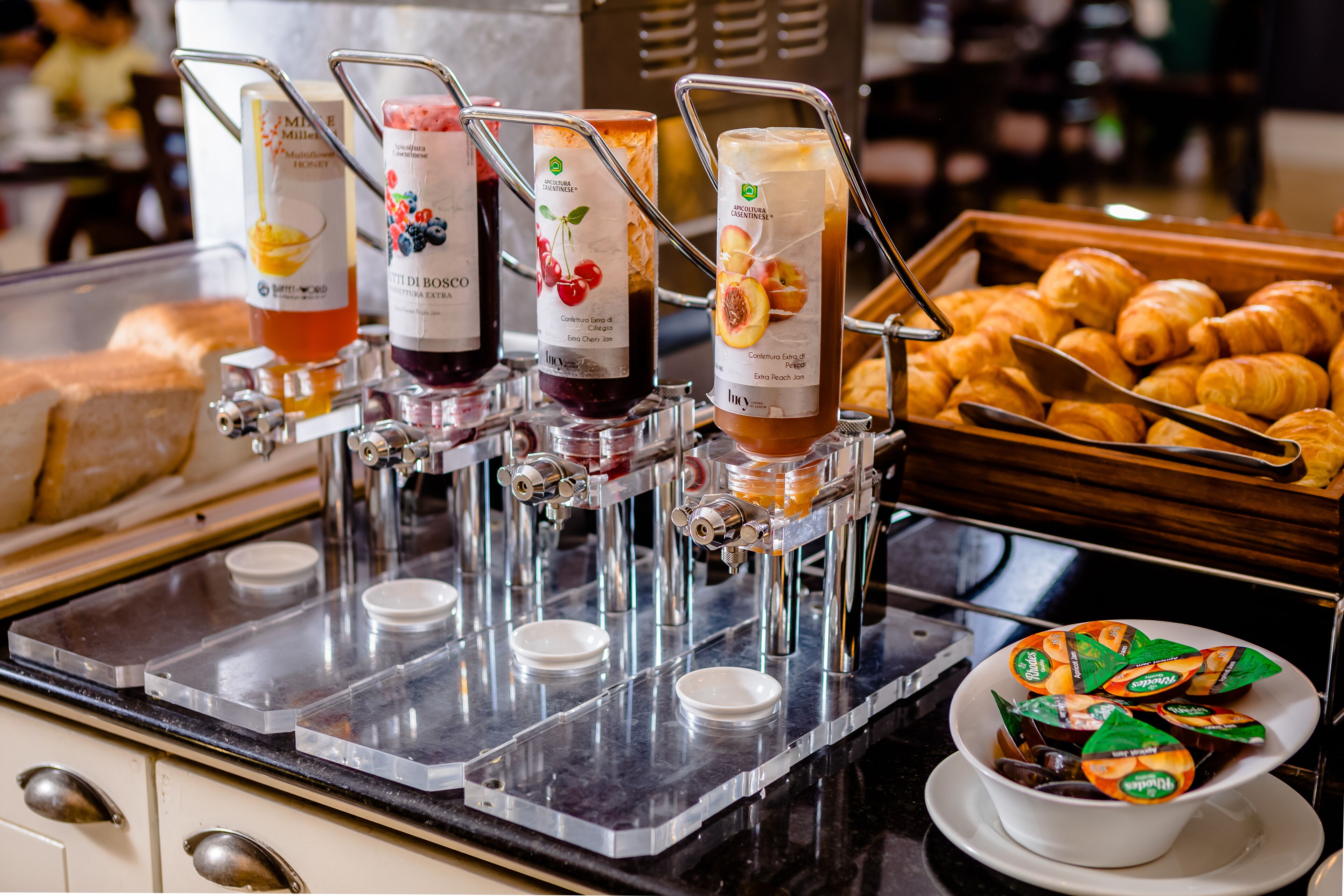 Een ontbijtbuffet met diverse jusdarm, een schaal croissants en een kommetje yoghurtbekers.