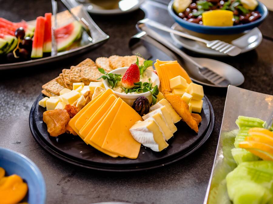 Una selección de quesos, galletas y frutas en un plato.