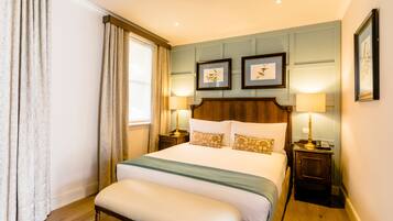 Habitación de hotel con una cama grande, dos mesitas de noche, un banco y cuadros en la pared.