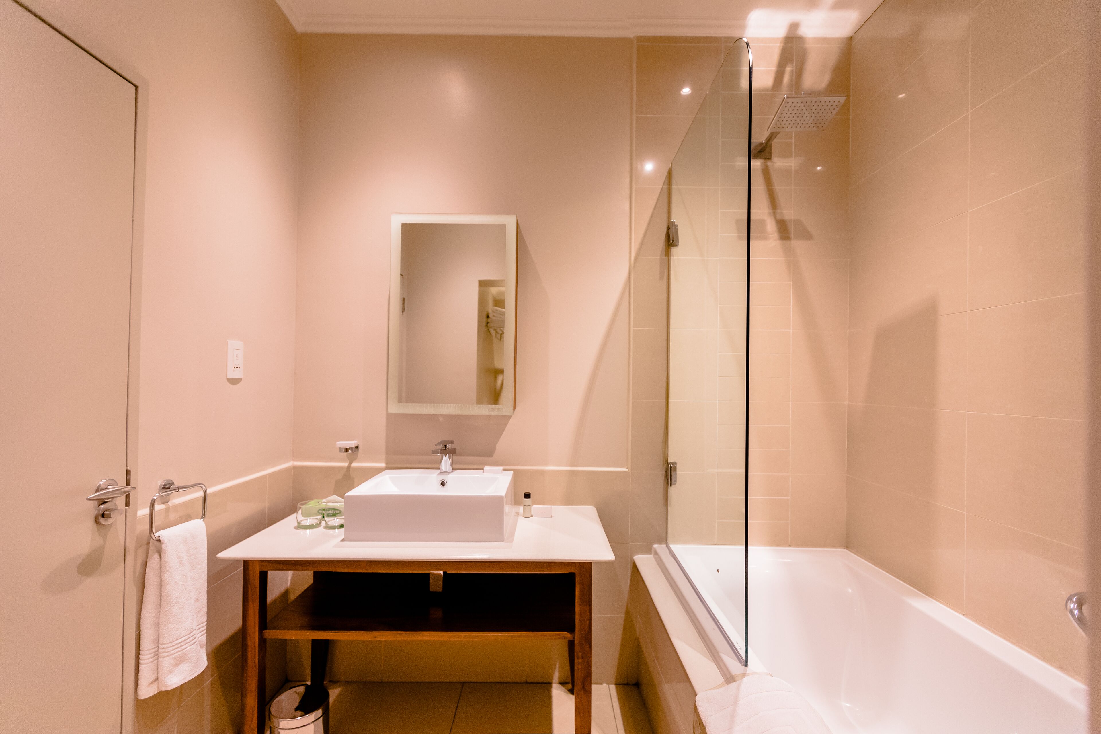 A modern bathroom with a glass-enclosed shower, a sink with a mirror above it, and a bathtub.