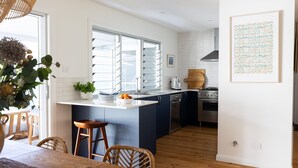 A modern kitchen with a central island, stainless steel appliances, and a view through large windows.