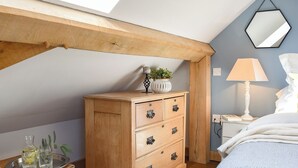 A bedroom with a wooden dresser, a bedside table with a lamp, and a mirror on the wall. - 1 bedroom accommodation in Ewelme (Ewelme)