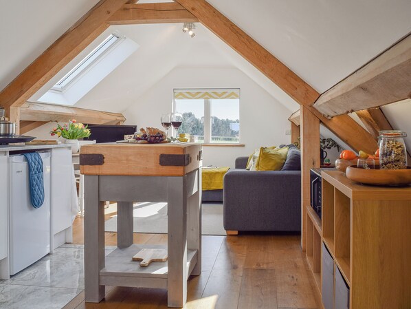 A cozy loft-style room with a kitchen area, a dining table, and a comfortable seating area.