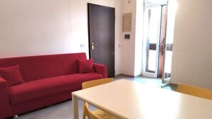 A room with a red sofa, a white table, and a yellow chair. - Boffy Houses (Lecce)