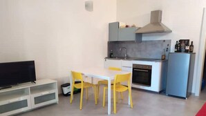 A compact living space with a dining area, kitchenette, and a TV. - Boffy Houses (Lecce)