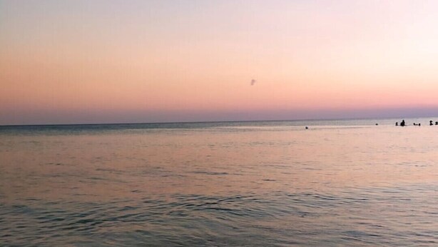 A calm sea at sunset with a few people in the distance. - Boffy Houses (Lecce)