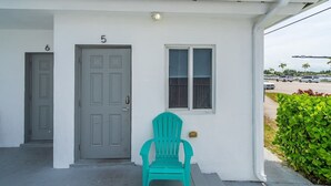 A white building with two doors, numbered 5 and 6, and a green chair outside. - Beach Studio · 2 Min Walk to Hollywood Broadwalk (Hollywood)