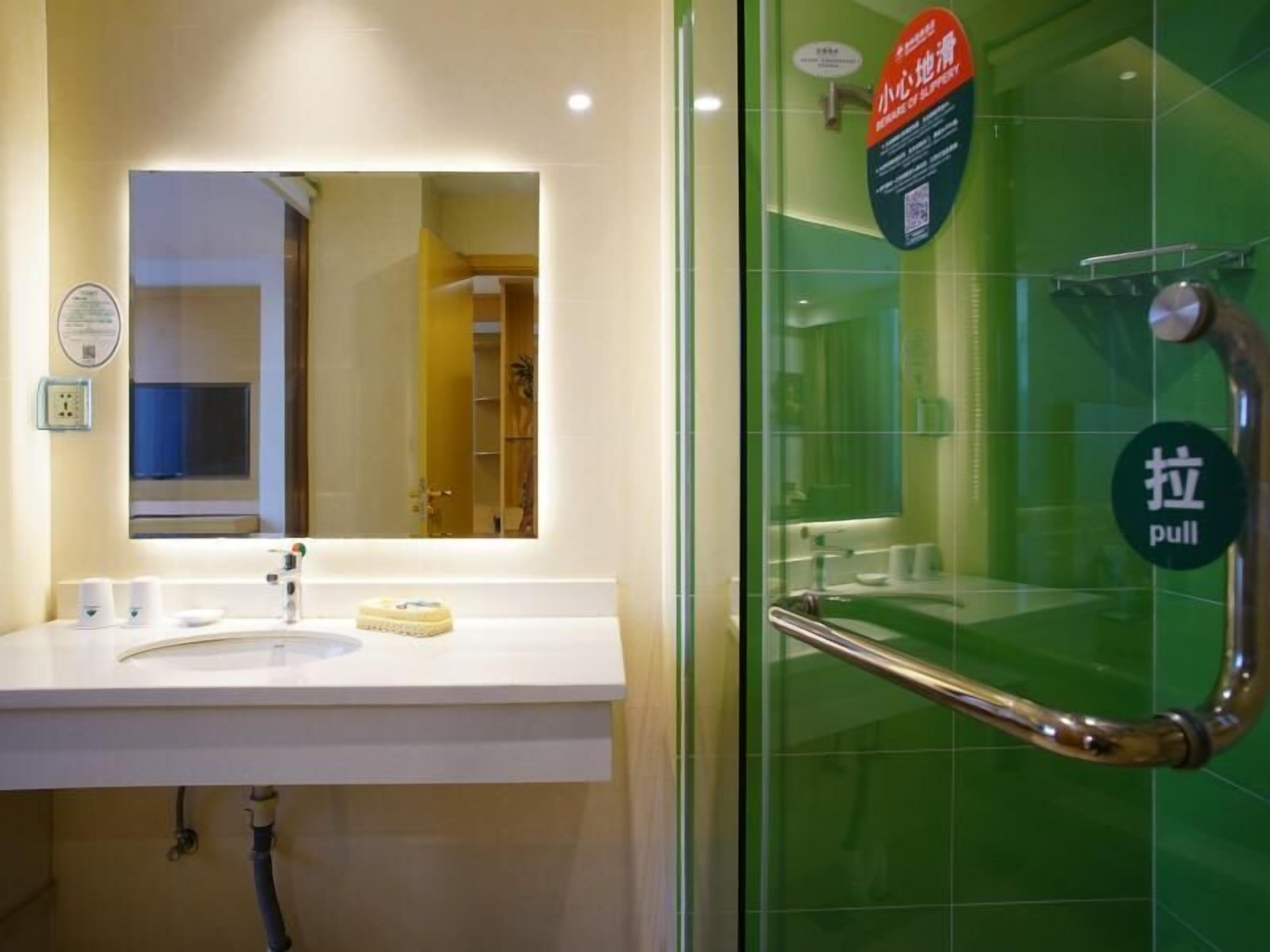 A bathroom with a white sink, mirror, and a glass door with a pull handle.
