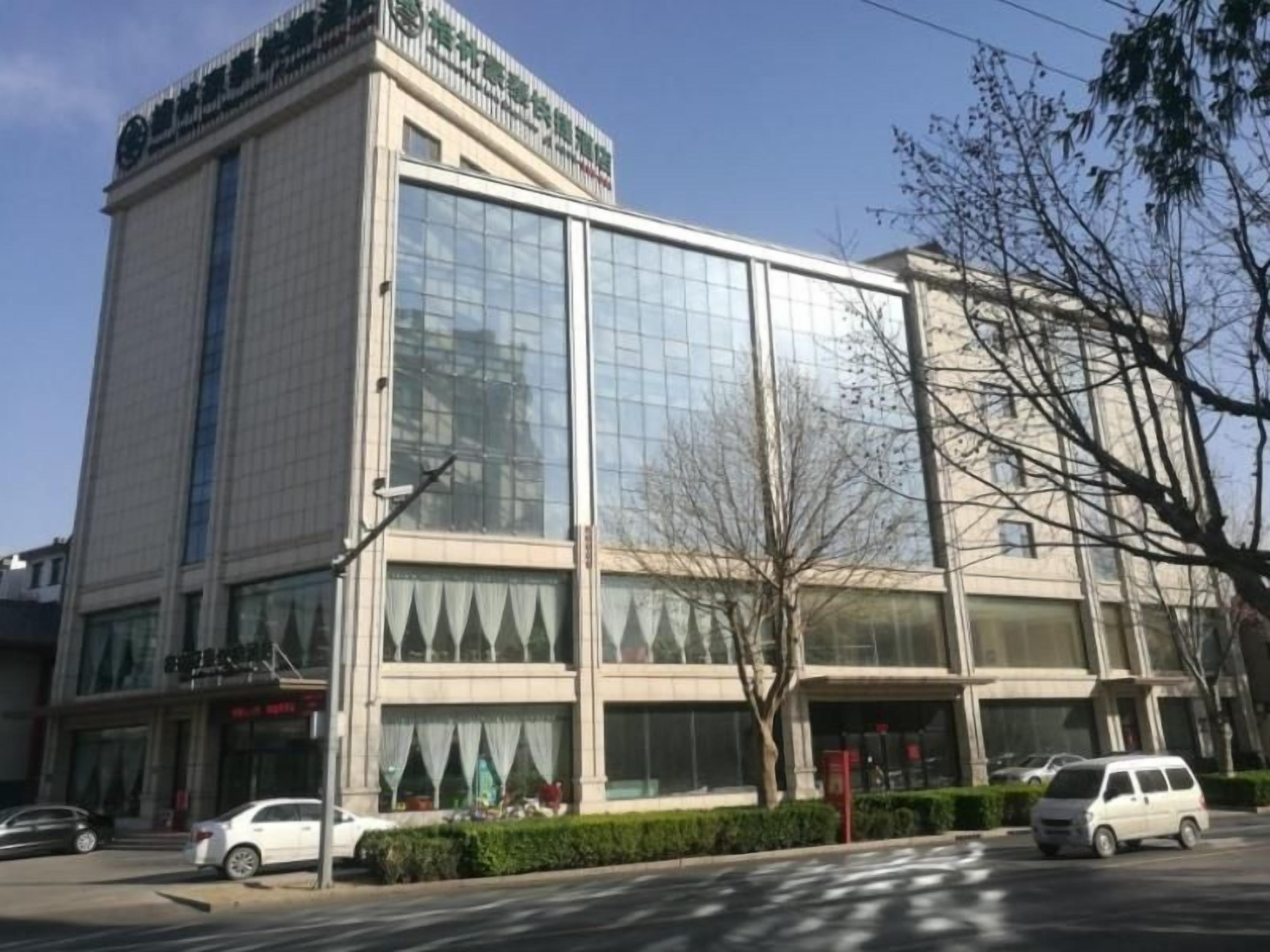 Un bâtiment moderne doté de grandes fenêtres en verre, d’une façade plate et d’une entrée bien visible, marquée par une porte rouge.