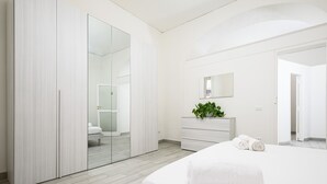 Une chambre à coucher moderne avec un grand lit, une armoire, une commode et un miroir.