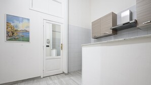 Une cuisine moderne avec des meubles blancs, une hotte en acier inoxydable et un dosseret carrelé.