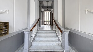 A grand staircase with marble steps and wooden railings leading to a doorway.