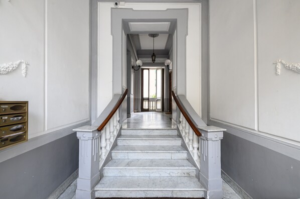 A grand staircase with marble steps and wooden railings leading to a doorway.