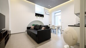 A modern living room with a black sofa, a flat-screen TV, and a unique egg-shaped chair.