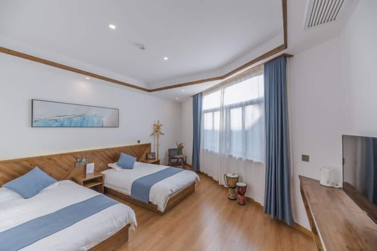 Two single beds with wooden headboards, a flat-screen TV, and a table with a lamp.