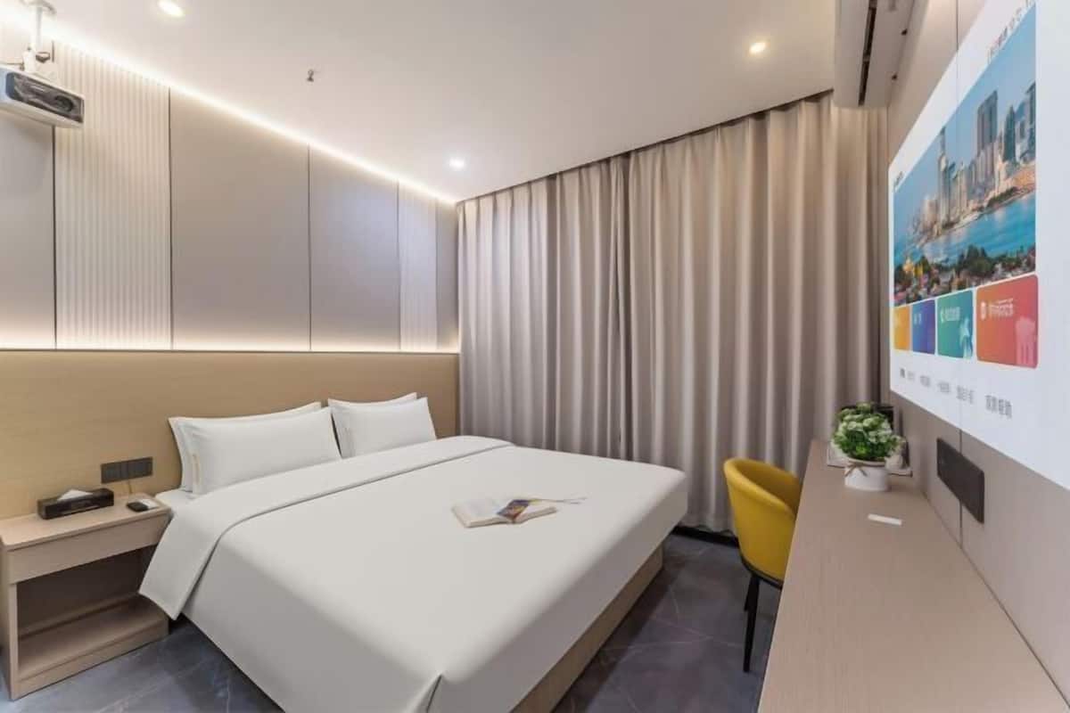 Une chambre d’hôtel moderne avec un grand lit, une table de chevet et un petit bureau avec une chaise.
