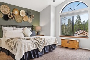 Relax in this serene bedroom with a large bed, nightstand, and stunning forest view.
