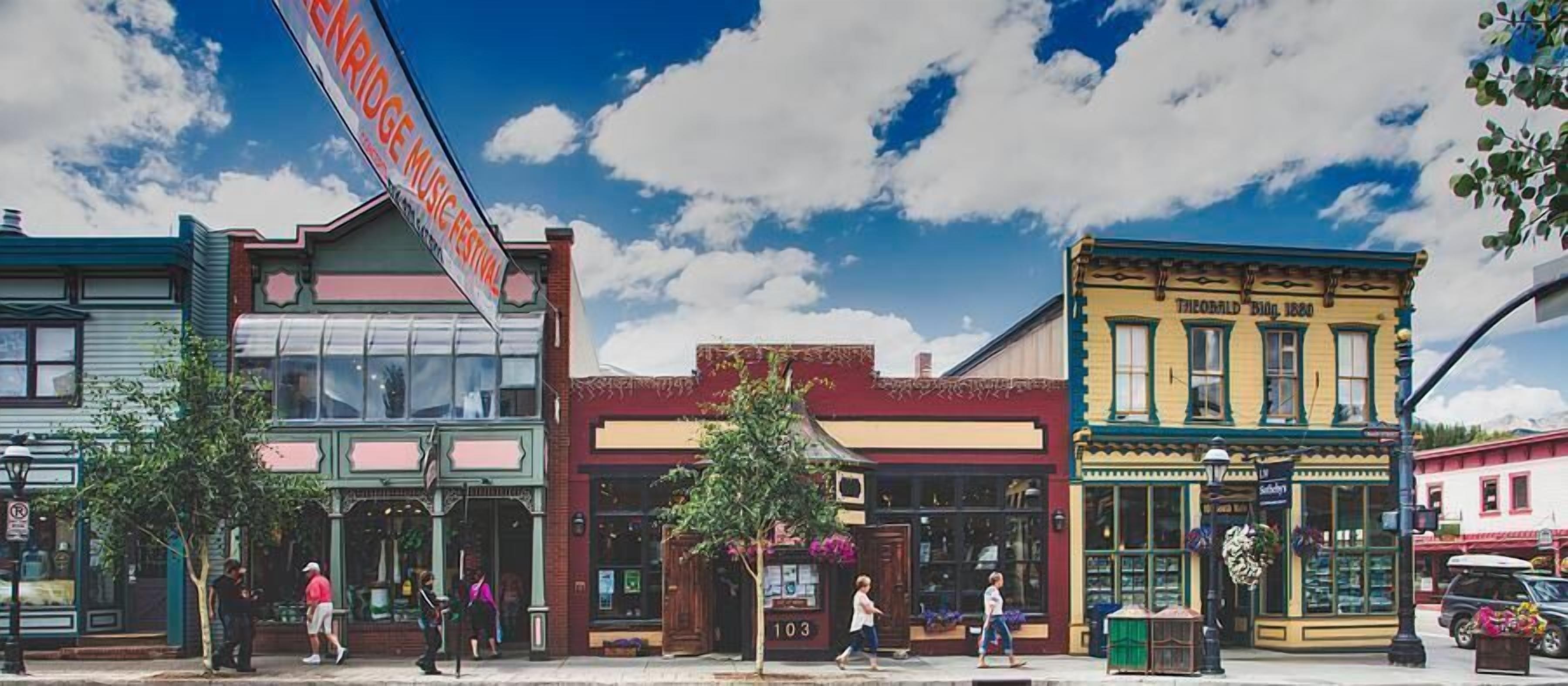 A street with buildings, including a theater with a sign for a music festival.