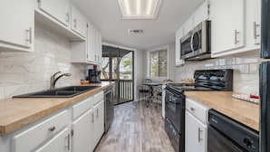 A modern kitchen with white cabinets, a black stove, and a microwave. - South Shore Updated 2 Bdrm! Hot tub/Mini-Golf/Tennis/Pickleball & More! (Hot Springs)