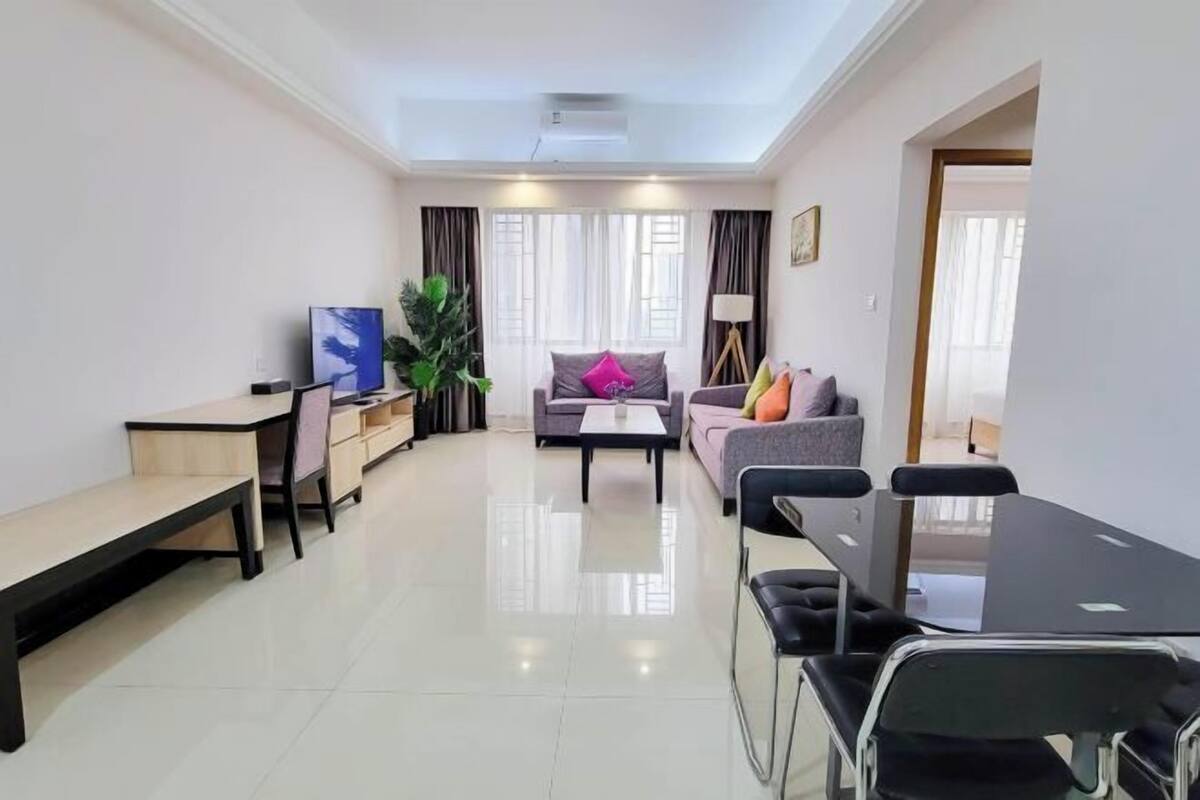A modern living room with a sofa, coffee table, and a dining table with chairs.