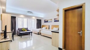 A hotel room with a bed, a desk, a chair, a sofa, and a TV. - Haili Apartment (Guangzhou)