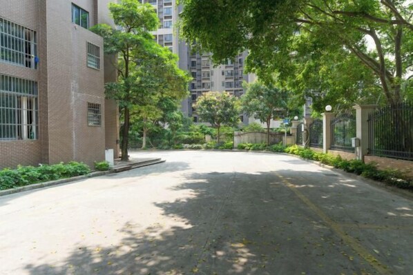 A quiet residential street with brick buildings, trees, and a gated entrance. - Haili Apartment (Guangzhou)