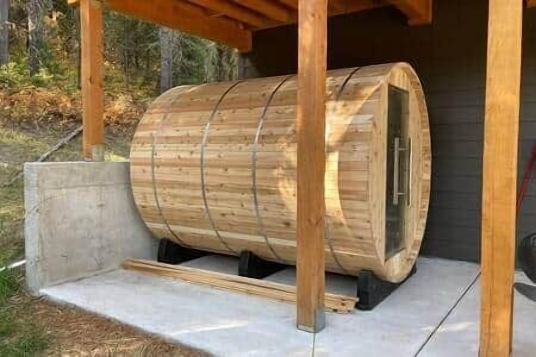 A wooden barrel structure with a concrete base and metal supports, situated outdoors with a natural backdrop.