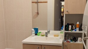 Une salle de bain avec une baignoire, un lavabo équipé de produits de toilette et un miroir au-dessus du lavabo.