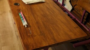 Un bureau en bois, une chaise violette, un canapé bleu et un meuble en bois à l’arrière-plan.