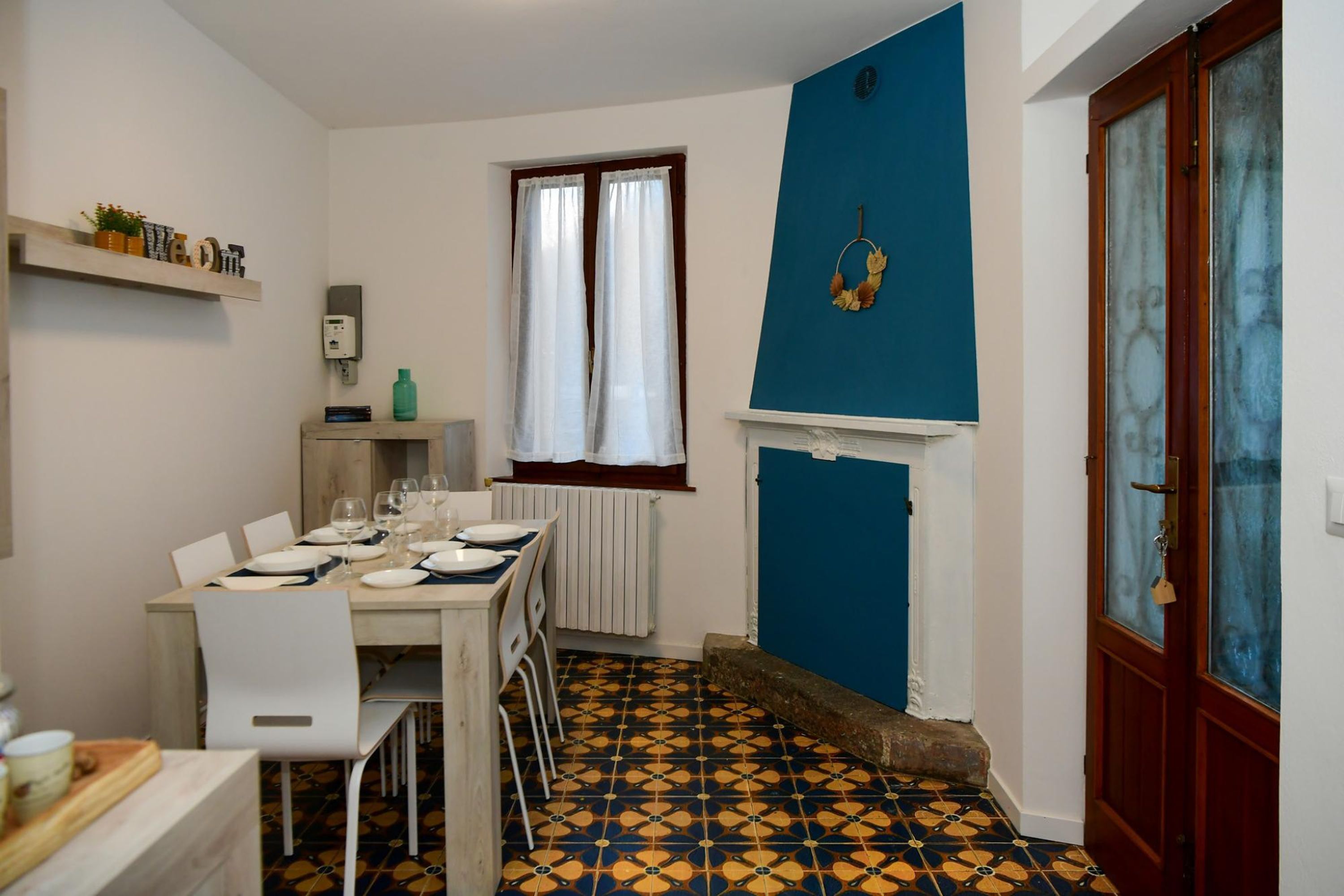 A compact dining area with a table set for four, a radiator, and a window with curtains.