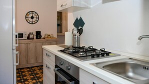 A kitchen with a gas stove, a sink, a microwave, and a clock on the wall. - Quadrifoglio by Wonderful Italy (Bellagio)