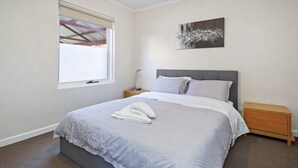A bedroom with a bed, a nightstand, a window with blinds, and a wall-mounted artwork. - Hurtle Sq Hideaway - Parking, Central, Ground Flr (Adelaide)
