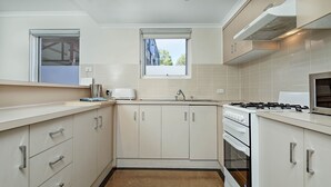 A compact kitchen with white cabinets, a built-in oven, a gas stove, and a window above the sink. - Hurtle Sq Hideaway - Parking, Central, Ground Flr (Adelaide)
