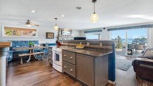 A modern kitchen with a large island, wooden flooring, and a view to the outside. - Epic Views: Hot Tub, 3BR/3BA, Sleeps10, Remote Retreat! (Lakebay)