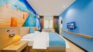 Habitación de hotel con cama, mesita de noche, lámpara, televisión y un mural de un muelle.