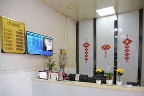 A reception desk with a computer monitor, a telephone, and a plant. - Puning Shi Hai Apartment (Puning)