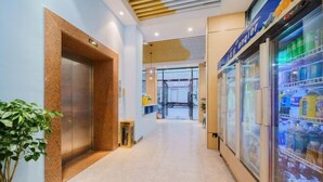 Un pasillo de hotel con un ascensor moderno, una máquina expendedora y un refrigerador exhibidor.